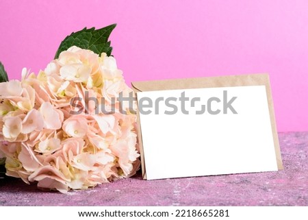 A kraft envelope with a hydrangea flower on a pink background. Invitation layout. Space for copying. Mother's Day, March 8, birthday, wedding, anniversary.