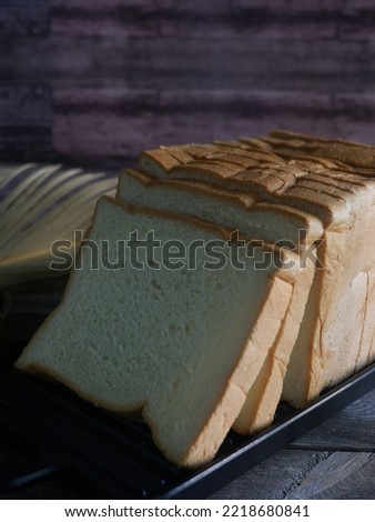 Sliced Bread on black tray with a cup of tea on the wooden table. Breakfast. Morning vibe. White Bread. Homemade bread.  Different light side. Still Life Photography. Roti Tawar. Baking. 