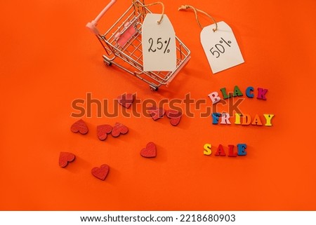 Shopping cart and Black Friday text with wooden letters outlined and discounts isolated on orange color. Black Friday discounts. black friday shopping cart