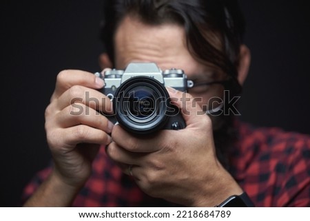 A bearded photographer taking a photo with his mirrorless or an slr retro vintage camera