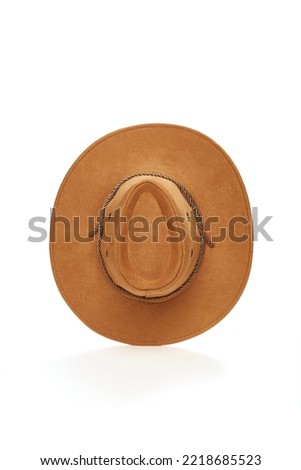Close-up shot of a light brown wide-brimmed cowboy hat with a chin strap. The men's cowboy hat is isolated on a white background. Top view. Royalty-Free Stock Photo #2218685523