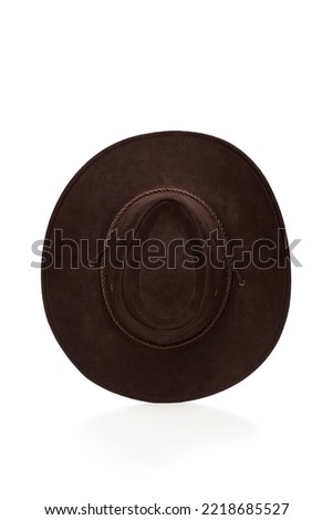 Close-up shot of a dark brown wide-brimmed cowboy hat with a chin strap. The men's cowboy hat is isolated on a white background. Top view.