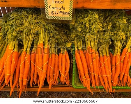 The top down, close up view of a wooden shelf filled with fresh, local bunches of carrots for sale.