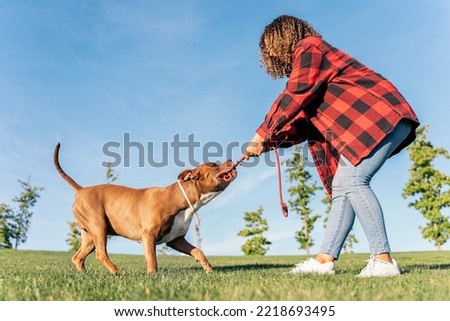 Unrecognized woman playing in the park with her purebred dog and having fun.