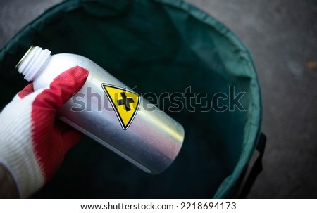 A black cross in a yellow triangle.Disposal of harmful waste. Throw the bottle of chemicals in the trash.