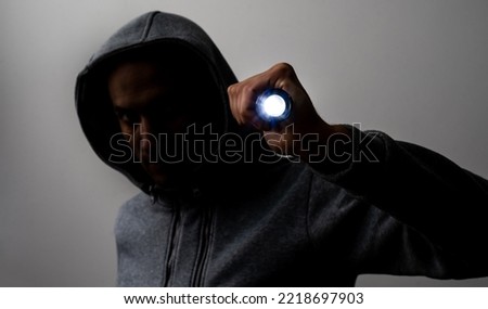 Close up portrait of a courageous man in a deep dark hood on a black background. The concept of secrecy of secrets and people hiding from the government. Hackers and thieves. Low key.