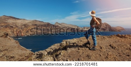 woman with backpack standing on cliff and looking to the ocean. mountain trekking and hiking. banner with copy space