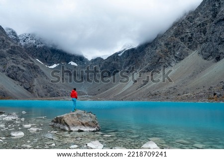 Woman enjoys  Blaisvatnet, Blue lake is a polular hiking destination, with mountains of the Lyngen Alps, Lyngenfjord, Troms og Finnmark, Norway - stock photo