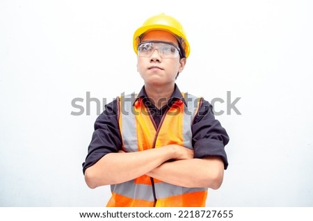 Portrait of a young confident engineer or construction worker in safety yellow helmet and orange vest