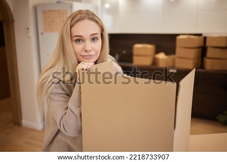 Caucasian girl taping boxes for moving in new apartment.