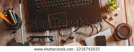 laptop is a mix of office supplies and gadgets on the background of a wooden table. Top view. The concept of coworking, remote work online, e-learning letters my job