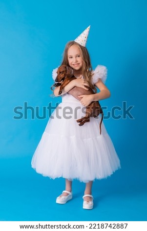 girl in a white fluffy elegant dress with a dachshund dog in her arms. High quality photo