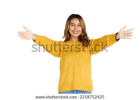 Attractive positive young asian brunette woman in yellow sweater on white background. hug concept.