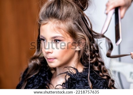 Make-up masters and a hairdresser work on a young girl in a beauty salon to prepare for a photo shoot. Amazon style. Beautiful makeup and bright eyes