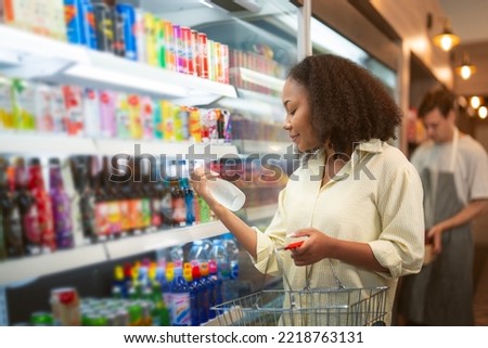 An African american woman buy a bottle of milk from refrigerator cold in convenience store for drink at home Royalty-Free Stock Photo #2218763131