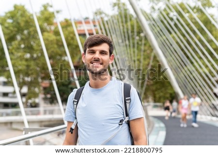 Portrait of a young happy caucasian tourist man in the Bilbao bridge in the street