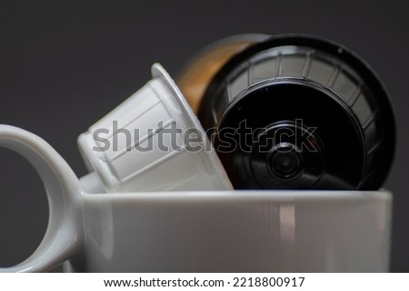 Caffeine hot drinks and objects concept - white black capsules for coffee machine on black background  selective focus