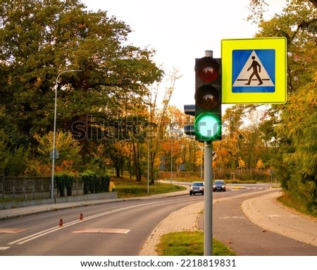 Pedestrian crossing sign, traffic light with green light for cars.