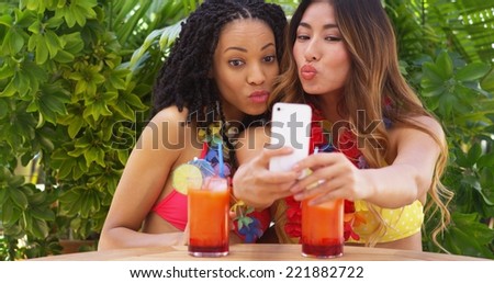 Black and Asian women taking selfie while on tropical vacation