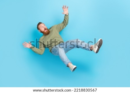 Full size photo of handsome young man frightened falling down slipping dressed stylish khaki outfit isolated on aquamarine color background Royalty-Free Stock Photo #2218830567