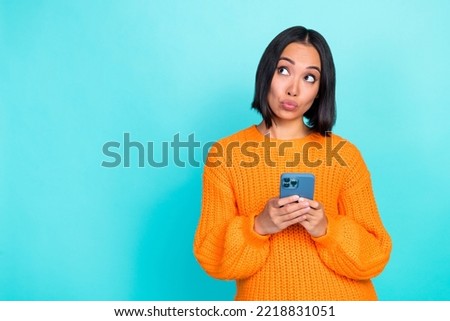 Photo of positive dreamy lady wear orange sweater reading modern device looking empty space isolated turquoise color background