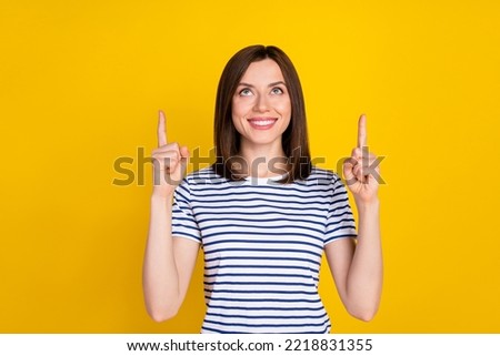 Photo portrait of stunning young woman fingers point look up empty space wear stylish striped garment isolated on yellow color background