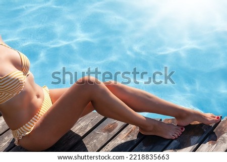 Woman legs on wooden deck near swimming pool. Summer vacation
