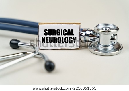 Medical concept. On a gray background, a stethoscope and a cardboard sign with the inscription - SURGICAL NEUROLOGY