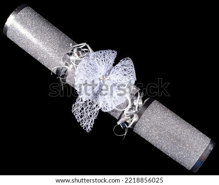 A traditional Christmas Cracker pictured over a black background.