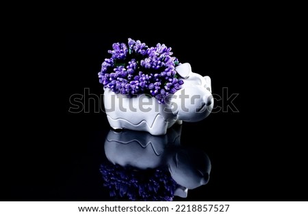 A close up shot of ceramic vase in the form of a dog with flowers The porcelain vase has fluted surface. The vase with a bunch is isolated against the black background. Bright reminding of season.