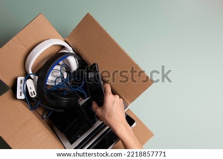 Woman hand collect old used computers, digital tablets, smartphones, electronic devices to cardboard box. Top view. Donation, charity, e-waste, electronic gadgets for reuse, refurbish, recycle concept Royalty-Free Stock Photo #2218857771