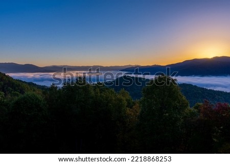 Beautiful view from above the clouds of the morning sun beginning to peek up over the distant mountain 