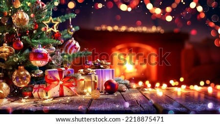 Gift Under Christmas Tree With Ornament In Interior With Fireplace And Abstract Defocused Lights