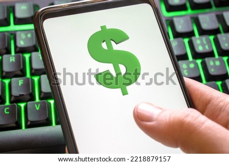 Smartphone with dollar symbol on screen phone with technology green colored keyboard background