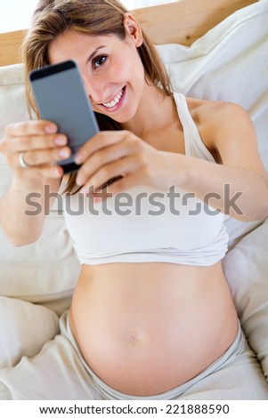 Portrait of pregnant woman taking a self-portrait with her smartphone.