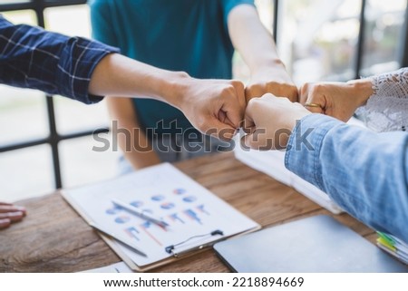 Group of young businessmen in Asian suits clasping hands Stack your hands to brainstorm to complete tasks on a given project. Passionate and excited about their work, and success concept.