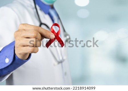 Doctor holding red ribbon on cancer day concept.Awareness symbolic of lymphoma ,Pancreatic and Testicular Cancer.
