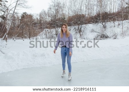 Lovely young woman riding ice skates on the ice rink. Girl skating on ice in a winter frosty day