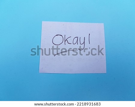 Okay writing on paper on a blue background.