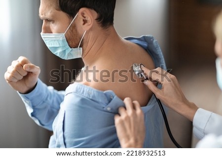 Pulmonology Concept. Unrecognizable Doctor Woman Checking Male Patient's Breathing With Stethoscope, Professional Pulmonologist Doing Lungs Check Up To Sick Man In Medical Mask, Closeup Shot Royalty-Free Stock Photo #2218932513