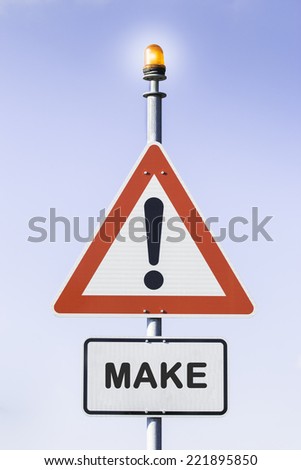 White road triangle with a red frame on a mast  with warning light on top in front of a blue sky. A second rectangular sign warns about MAKE. First of three pictures with the message MAKE MORE MONEY