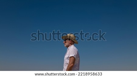 Adult man in cowboy hat against blue sky