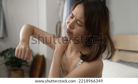 close up view young asian girl massage painful shoulder. Attractive woman sitting on bed and holding painful neck with another hand. illness lady having upper arms muscle problems and release pain Royalty-Free Stock Photo #2218966349