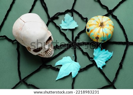 Halloween composition with human scull, pumpkin, leaves and spider web on color background