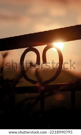 Silhouette of a fence that looks like a sign of love in the evening