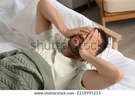 Sleepless man lying in bed at home Royalty-Free Stock Photo #2218995213