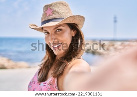 Brunette woman enjoying a summer day at the beach taking a selfie picture