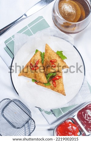 a beautiful picture of samosa on a plate with chili sauce and tomato sauce, serve with ice tea