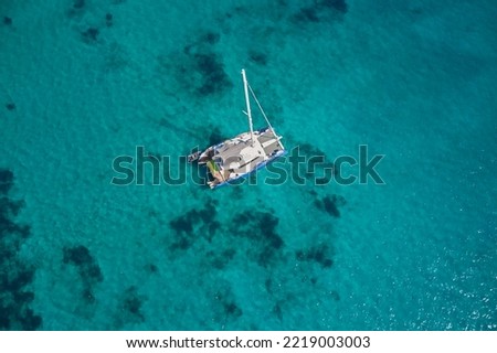 White catamaran boat at anchor, transparent turquoise water aerial view. White big catamaran blue water top. Royalty-Free Stock Photo #2219003003