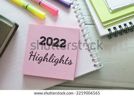 Sticky note pile with the inscription 2022 highlights on desk with stationery items. Major events, overview, looking back at 2022 year concept. Royalty-Free Stock Photo #2219006565